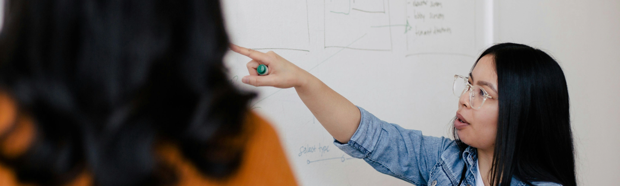 A woman pointing to a information on a whiteboard