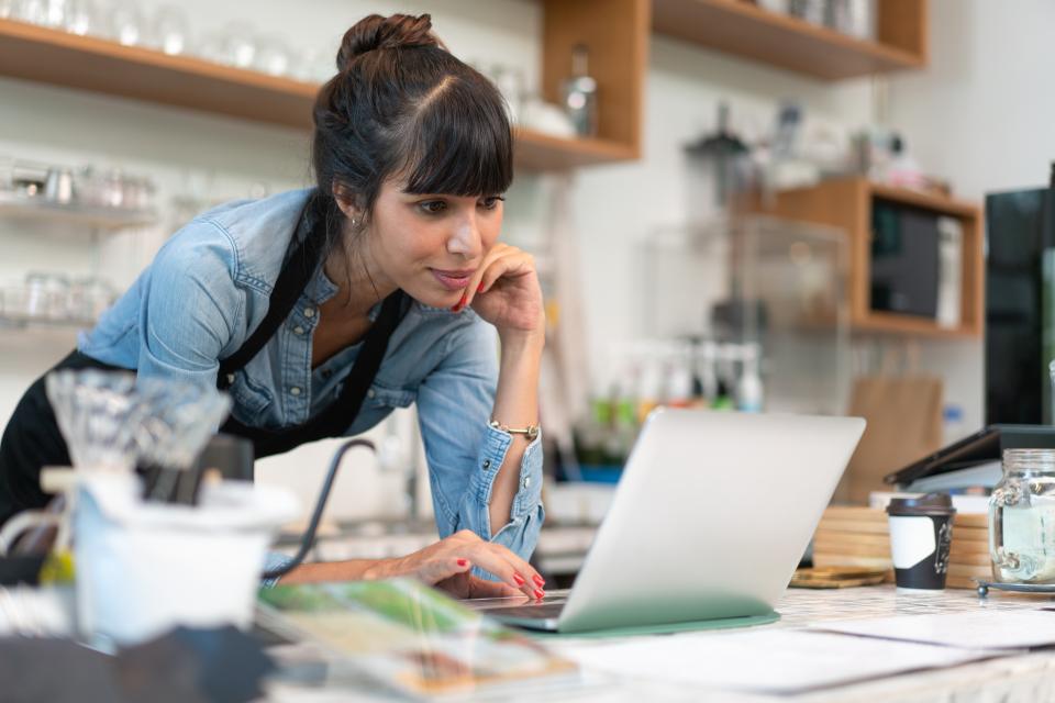 A female entrepreneur works on a laptop from her small business.