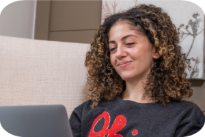 Smiling woman on sofa looking at her laptop